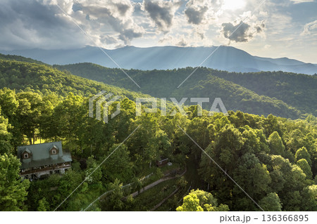 House on hill and Mount Mitchell in North Carolina Appalachian mountains. Lush forest illuminated with bright setting sun. Aerial view of colorful sunset in wild mountains. Beautiful nature landscape House on hill and Mount Mitchell in North Carolina Appalachian mountains. Lush forest illuminated with bright setting sun. Aerial view of colorful sunset in wild mountains. Beautiful nature landscape 136366895