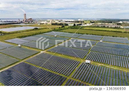 Modernization of power infrastructure at fossil fuel power plant. Solar photovoltaic panels illustrate the region move toward sustainable and renewable energy sources 136366930