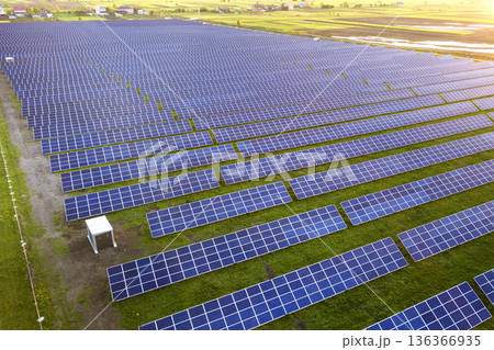 Large field of solar photo voltaic panels system producing renewable clean energy on green grass background. Large field of solar photo voltaic panels system producing renewable clean energy on green grass background. 136366935