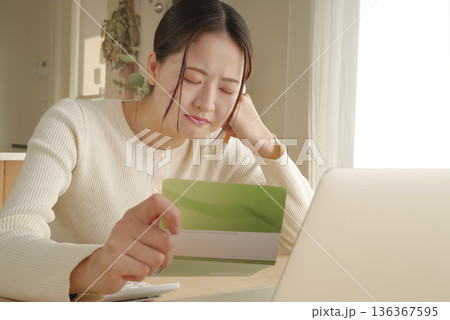 通帳をみてお金の管理をする女性 通帳をみてお金の管理をする女性 136367595