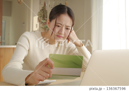 通帳をみてお金の管理をする女性 通帳をみてお金の管理をする女性 136367596
