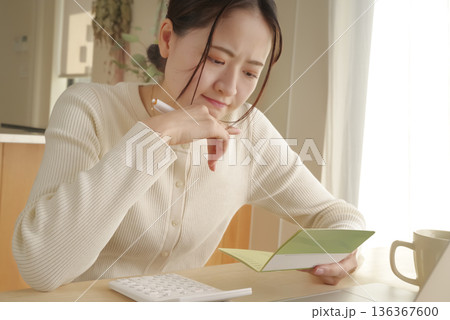 通帳をみてお金の管理をする女性 通帳をみてお金の管理をする女性 136367600