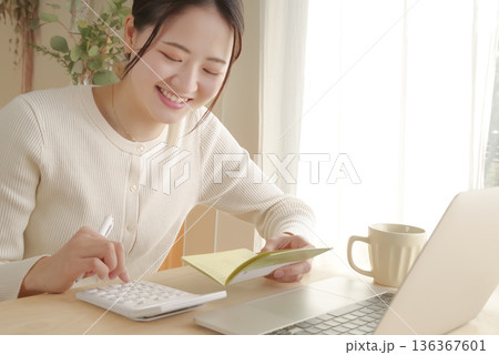 通帳をみてお金の管理をする女性 通帳をみてお金の管理をする女性 136367601