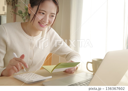 通帳をみてお金の管理をする女性 136367602