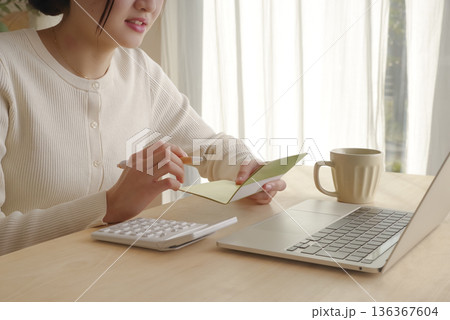 通帳をみてお金の管理をする女性 通帳をみてお金の管理をする女性 136367604