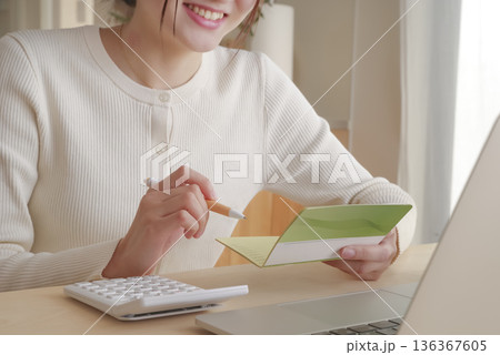 通帳をみてお金の管理をする女性 136367605