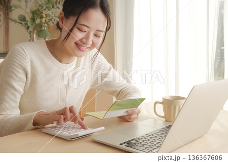 通帳をみてお金の管理をする女性 136367606