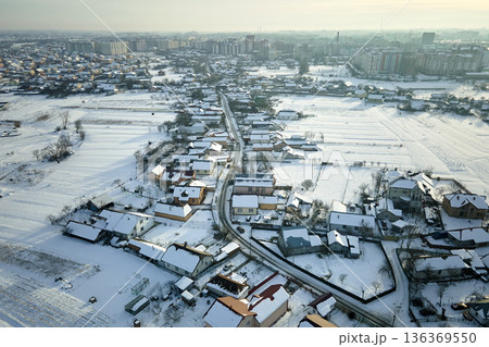 Aerial view of private homes with snow covered roofs in rural suburbs town area in cold winter 136369550