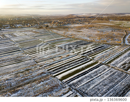 Top view of empty snowy fields patched landscape, dark horizon and bright sky on sunny winter day. Aerial drone photography concept. Top view of empty snowy fields patched landscape, dark horizon and bright sky on sunny winter day. Aerial drone photography concept. 136369600