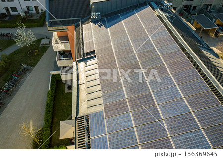 Aerial view of solar photovoltaic panels on a roof top of residential building block for producing clean electric energy. Autonomous housing concept. 136369645