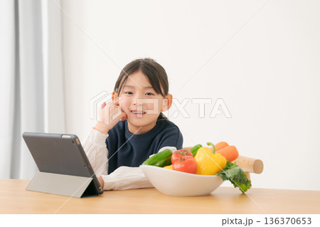 タブレットを見ながら野菜を持つ女の子 タブレットを見ながら野菜を持つ女の子 136370653