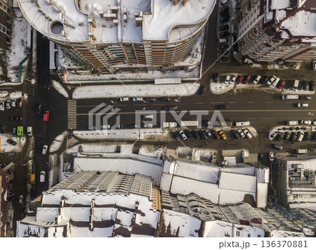 Aerial black and white winter top view of modern city with tall buildings, parked and moving cars along streets with road marking. Urban cityscape, view from above. 136370881