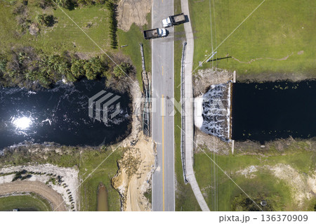 Damaged road bridge destroyed by river after flood water washed away asphalt. Rebuilding of ruined transportation infrastructure 136370909