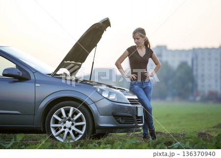 Young woman and a car with popped hood. Transportation, vehicles problems and breakdowns concept. 136370940