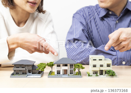 住宅模型を見ながら話し合いをする夫婦 住宅模型を見ながら話し合いをする夫婦 136373168