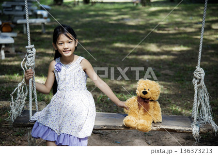Happy Child hug teddy bear in green park playground. Teddy bear best friend for little kids cute girl. Autism happy funny playing together on playground in happiness family feel love and warm hugs Happy Child hug teddy bear in green park playground. Teddy bear best friend for little kids cute girl. Autism happy funny playing together on playground in happiness family feel love and warm hugs 136373213