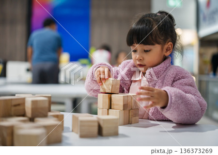preschool child girl concentrating on building tower with wooden block preschool child girl concentrating on building tower with wooden block 136373269