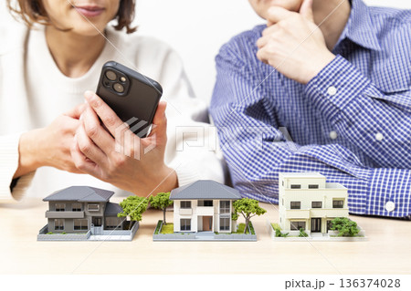 住宅模型を見ながら話し合いをする夫婦 136374028