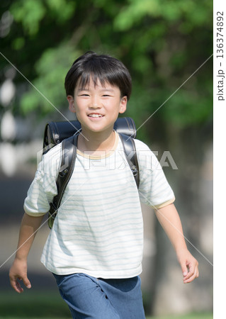 ランドセルを背負って走る少年の(男の子)男子のカメラ目線 ランドセルを背負って走る少年の(男の子)男子のカメラ目線 136374892