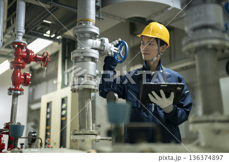 タブレットを持って点検作業を行うビルメンテナンススタッフ タブレットを持って点検作業を行うビルメンテナンススタッフ 136374897