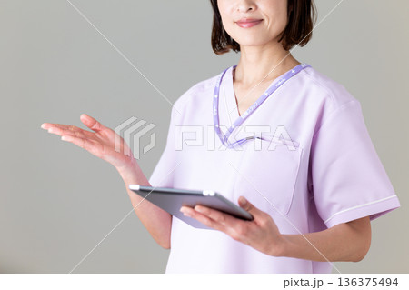 タブレットを持つ医療用スクラブ姿のミドル女性看護師 タブレットを持つ医療用スクラブ姿のミドル女性看護師 136375494