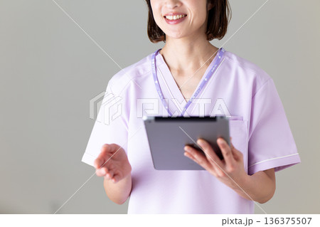タブレットを持つ医療用スクラブ姿のミドル女性看護師 136375507