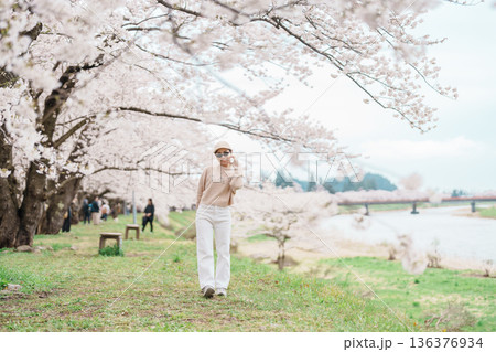 Woman tourist sightseeing Sakura Cherry Blossom in Spring. Happy traveler travel near Hinokinai River riverbank in Kakunodate town, Semboku District, Akita Prefecture, Japan. Landmark and Vacation Woman tourist sightseeing Sakura Cherry Blossom in Spring. Happy traveler travel near Hinokinai River riverbank in Kakunodate town, Semboku District, Akita Prefecture, Japan. Landmark and Vacation 136376934