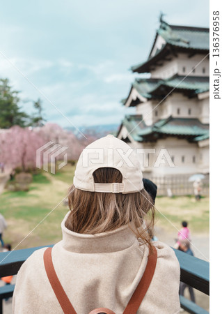 Woman tourist sightseeing Hirosaki Castle with Sakura Cherry Blossom in Spring, happy traveler travel in Hirosaki city, Aomori, Tohoku, Japan. Landmark famous in Japan. Travel and Vacation destination 136376958