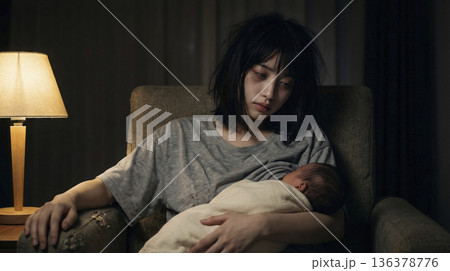 深夜の暗い部屋で疲れ切った表情で授乳をしている髪の乱れた日本人の母親 136378776