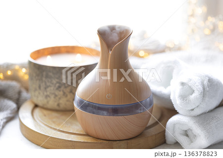 Cozy composition with essential oil aroma diffuser, towels and candles. 136378823