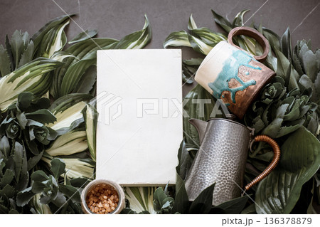 Cup with a teapot on a green leaf background 136378879