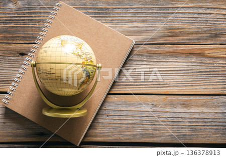 Earth globe and notebook on wooden background, top view. Earth globe and notebook on wooden background, top view. 136378913