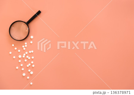 Flat lay, pills and magnifier on pink background, copy space. Flat lay, pills and magnifier on pink background, copy space. 136378971