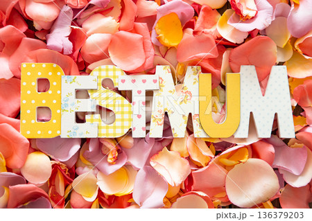 Best Mum written in multicolored wooden letters on bright background of fresh rose petals. 136379203