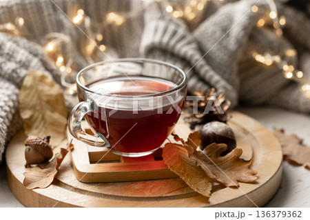 Autumn composition with a cup of tea, leaves and a knitted element. Autumn composition with a cup of tea, leaves and a knitted element. 136379362