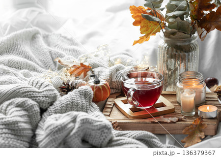 Autumn composition with a cup of tea, leaves and a knitted element. Autumn composition with a cup of tea, leaves and a knitted element. 136379367