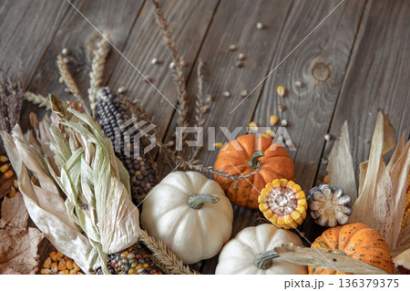 Autumn composition with pumpkins, corn and leaves on a wooden background. Autumn composition with pumpkins, corn and leaves on a wooden background. 136379375