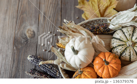 Close-up of pumpkin, corn and autumn leaves on a wooden background. Close-up of pumpkin, corn and autumn leaves on a wooden background. 136379376