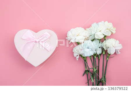 A bouquet of flowers, heart shaped gift box on pink background, flat lay. A bouquet of flowers, heart shaped gift box on pink background, flat lay. 136379522