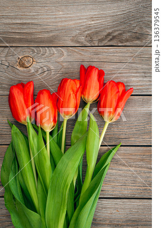 Bouquet of red tulips on a wooden background, top view. Bouquet of red tulips on a wooden background, top view. 136379545