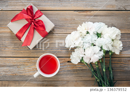 Bouquet of white flowers, gift box and a cup of tea on a wooden background. Bouquet of white flowers, gift box and a cup of tea on a wooden background. 136379552