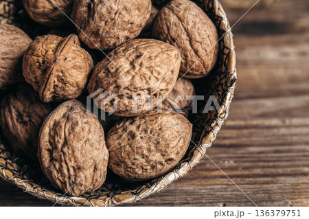 Close-up, whole walnuts in a wicker bowl on a wooden background. Close-up, whole walnuts in a wicker bowl on a wooden background. 136379751