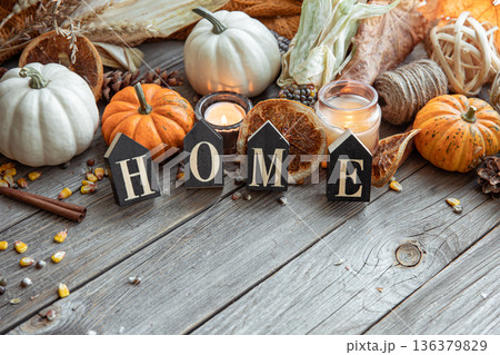 Cozy autumnal composition with decorative word home, candles, pumpkins and corn. Cozy autumnal composition with decorative word home, candles, pumpkins and corn. 136379829