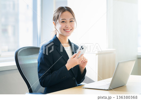 オフィスでスマホを持つビジネスウーマン 136380368