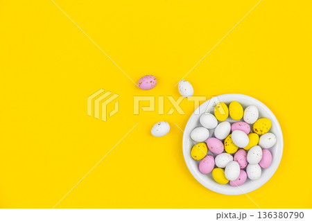 Plate with Easter eggs on a yellow background, top view. 136380790
