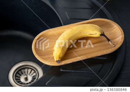 Ripe yellow banana in the kitchen near the sink. Ripe yellow banana in the kitchen near the sink. 136380846