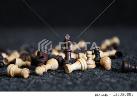 Scattered chess pieces on a blurred black background. 136380893