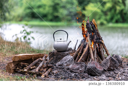 Small kettle is heated on a bonfire, outdoor recreation concept. Small kettle is heated on a bonfire, outdoor recreation concept. 136380910