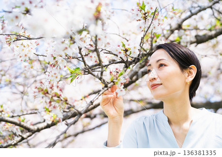 桜の花びらを見る若い女性 ライフスタイルイメージ 桜の花びらを見る若い女性 ライフスタイルイメージ 136381335