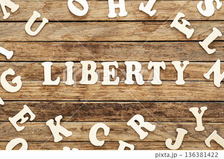 The word Liberty written on wood letters on wooden background, top view. The word Liberty written on wood letters on wooden background, top view. 136381422